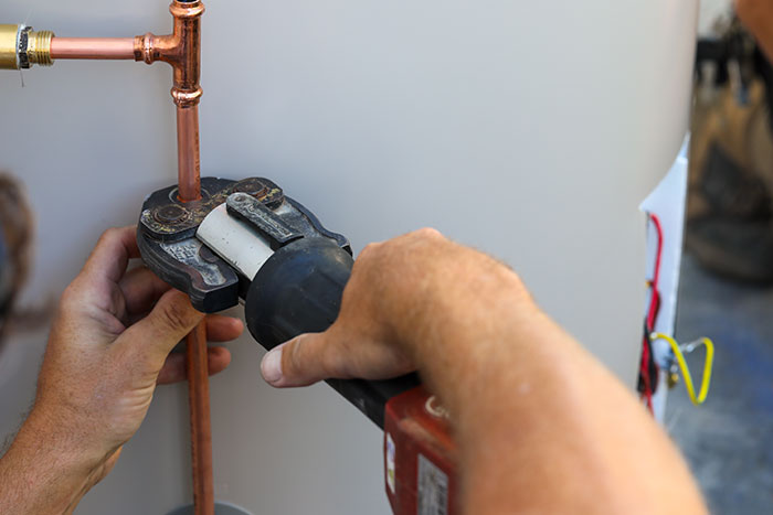 Plumber securing copper piping on a hot water system in North Lakes